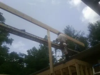 Carpenter setting a ridge beam over a new addition frame — Ice Dam Removal by Roofing Brothers in Gibbon