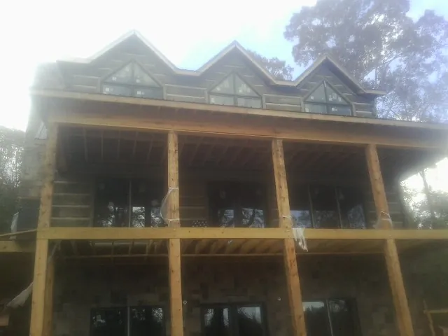 Dormers and porch framing on a large log home under construction — Roof Coating work by our crew in Gibbon