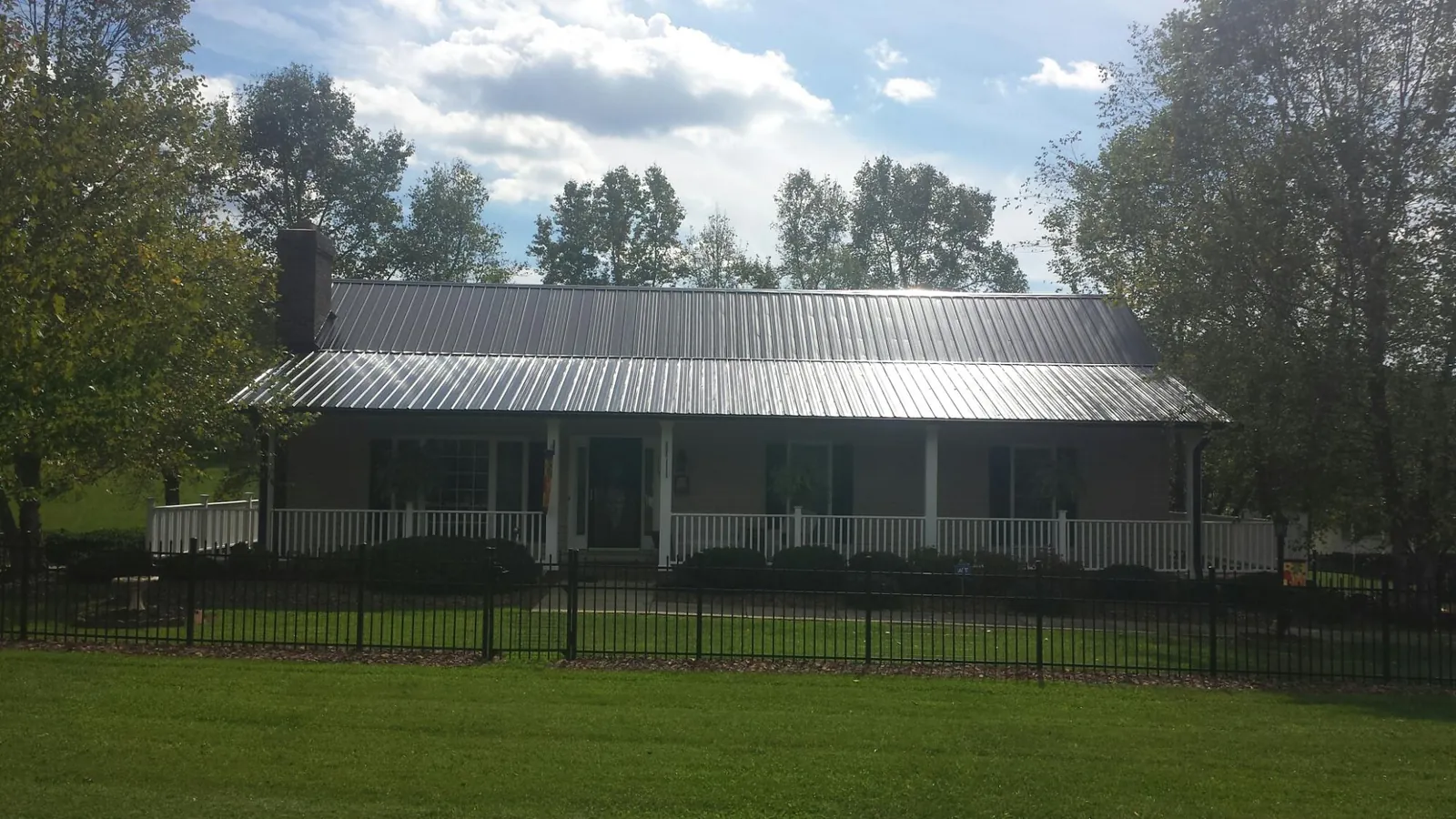 Gray metal roof on a brick ranch with a full width front porch — Gutter Guard Installation work by our crew in Gibbon
