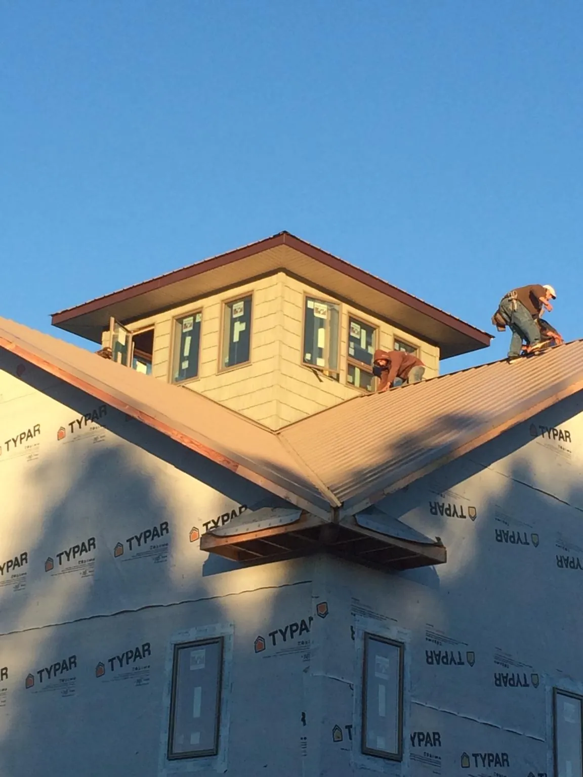 Roofers working around a rooftop cupola on a new metal roof at sunset — Roof Waterproofing in Gibbon by Roofing Brothers